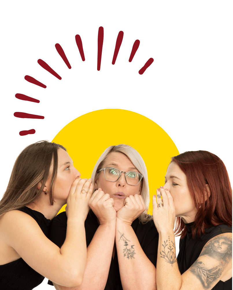 Hero Digital Lab team members whispering to a surprised colleague in a playful studio portrait.