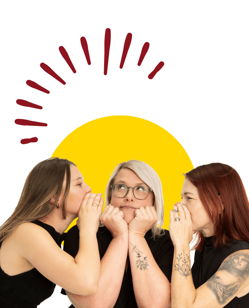 Three Hero Digital Lab team members sharing a playful whisper in a creative team photo.